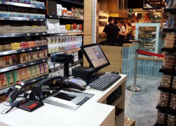 Sprzedawczyni sprawnie nabija kolejne produkty i wydaje klientom paragony z kasy fiskalnej