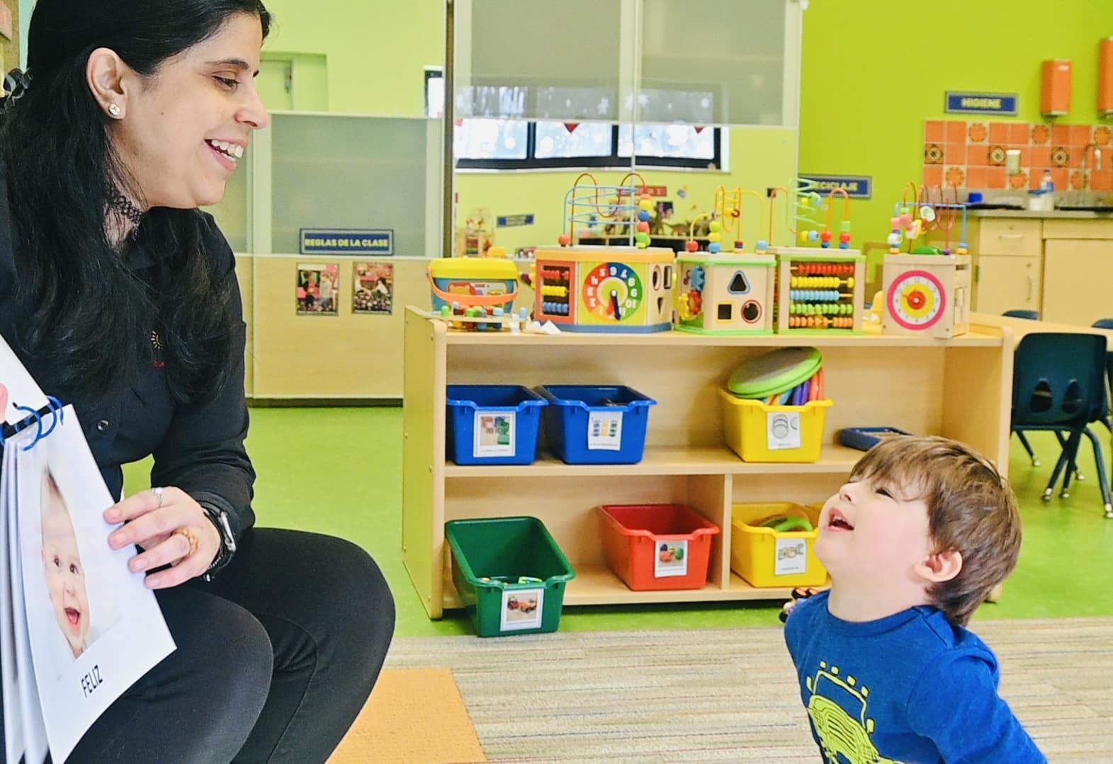 Przedszkolak słucha bajki w słuchawkach i pokazuje obrazki z książki