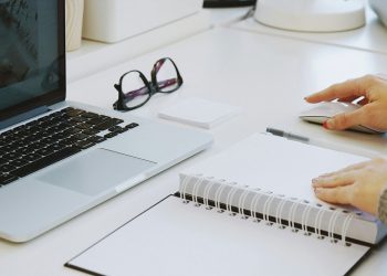 Osoba przy biurku z dokumentami umów cywilnoprawnych kalkulatorem i komputerem