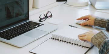 Osoba przy biurku z dokumentami umów cywilnoprawnych kalkulatorem i komputerem