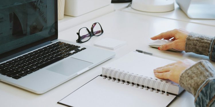 Osoba przy biurku z dokumentami umów cywilnoprawnych kalkulatorem i komputerem