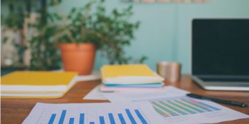 Laptop z aplikacją księgową obok budynku biura rachunkowego z pracownikami