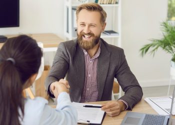 Młody przedsiębiorca podpisuje umowę pożyczki przy biurku z laptopem i planem biznesu