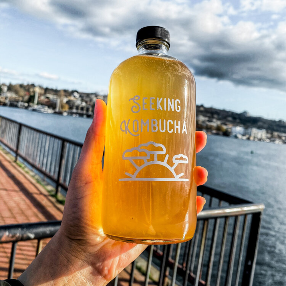 Mężczyzna nalewający kombuchę z słoika do szklanki w kuchni