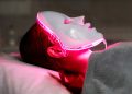 kobieta z maską LED na twarzy relaksuje się na kanapie w salonie