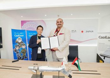 Dwóch biznesmenów w garniturach ściskających dłonie nad stołem z umowami