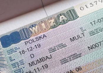 Pracodawca polski i uśmiechnięty cudzoziemiec przeglądają dokumenty przy biurkowym stole