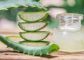 Fresh aloe leaves and aloe gel in the cosmetic jar on wooden table.