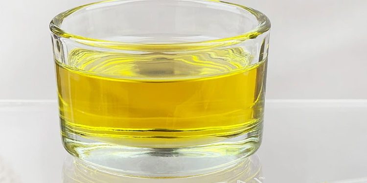 Ciemna butelka oleju z ostropestu obok świeżych kwiatów rośliny