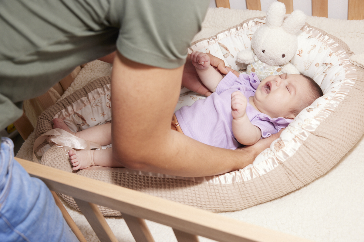 zakraplanie nosa przy katarze mama wkładająca krople do nosa niemowlęciu z uniesioną główką